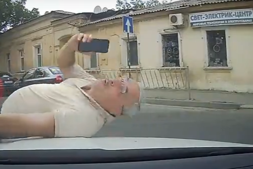 В Симферополе на капот авто бросился «неваляшка» с телефоном (видео)